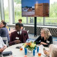 Group of event attendees sitting at table and chatting together